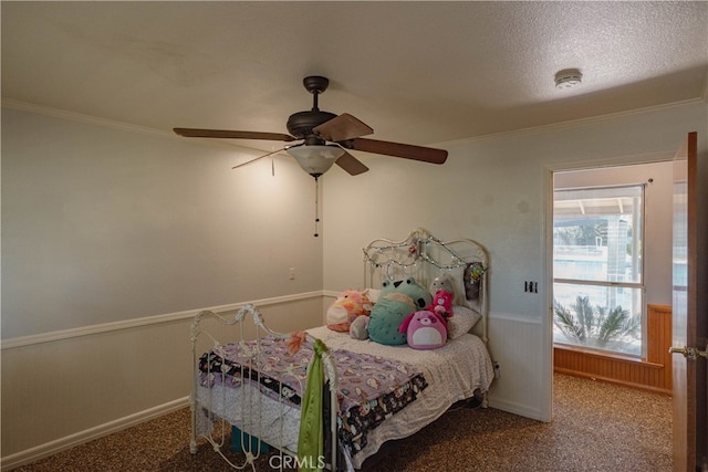 bedroom with carpet floors, a ceiling fan, ornamental molding, and wainscoting