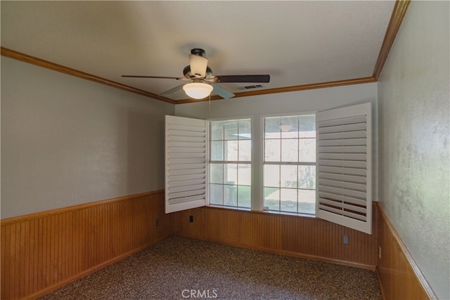 carpeted empty room with wooden walls, ornamental molding, and wainscoting