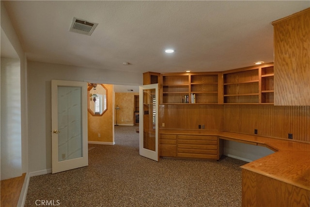 unfurnished office with visible vents, built in desk, recessed lighting, french doors, and carpet floors