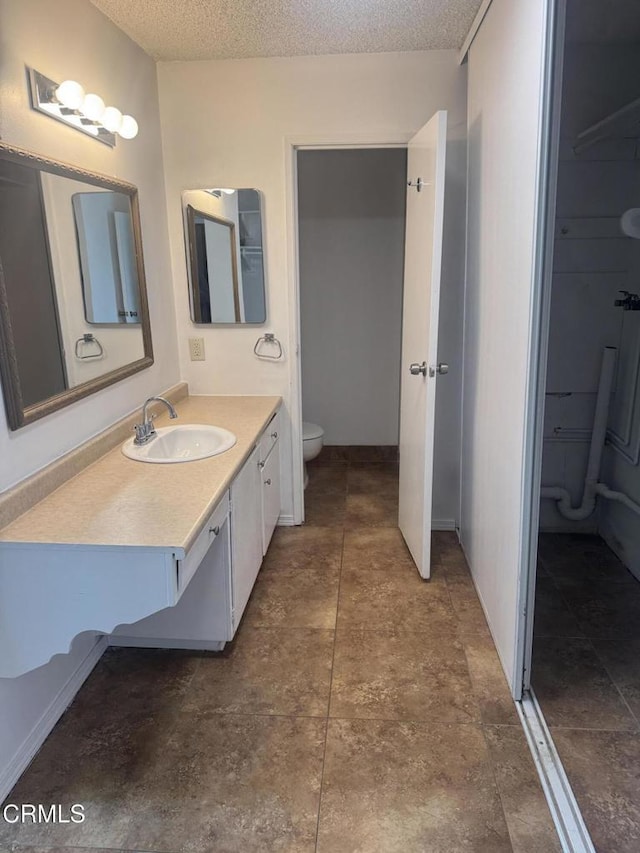 bathroom with a textured ceiling, toilet, and vanity