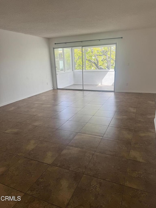 spare room featuring plenty of natural light, a textured ceiling, and baseboards