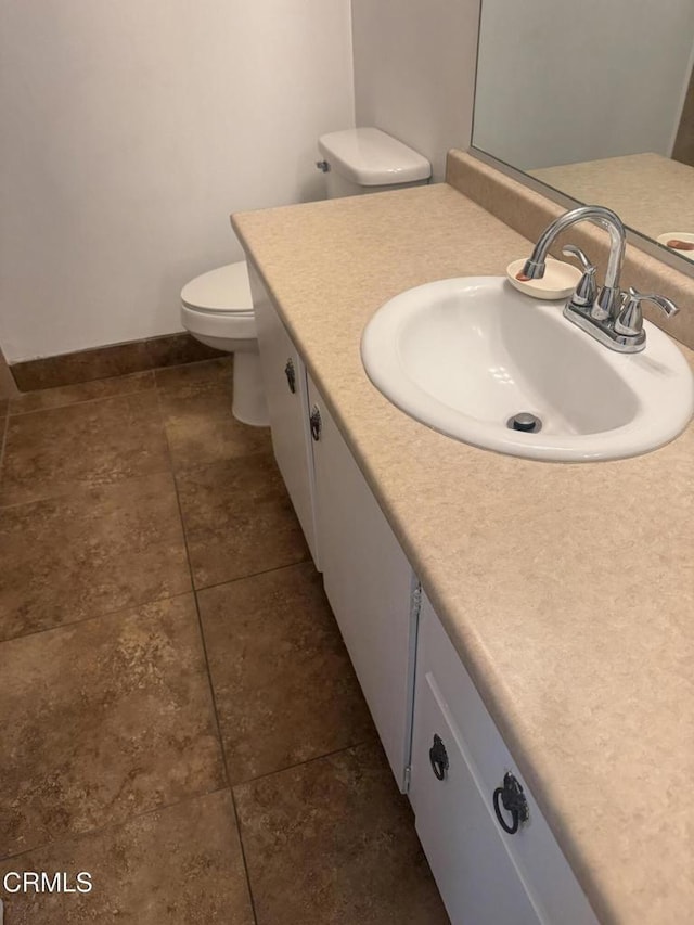 bathroom with baseboards, toilet, and vanity