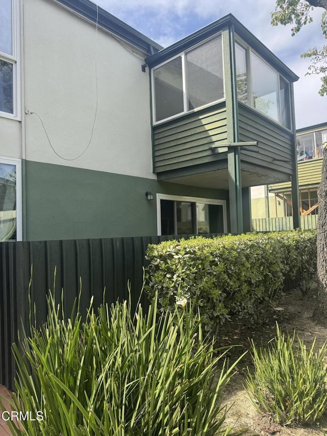 back of property featuring stucco siding and fence