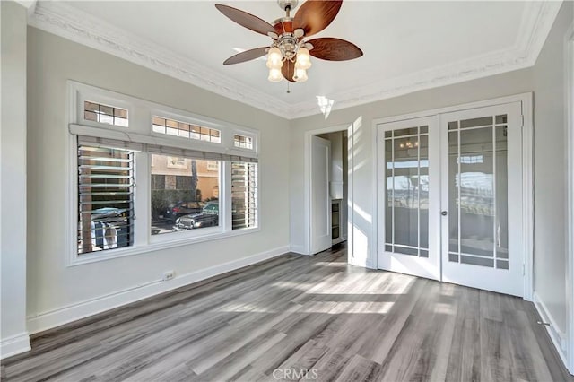 empty room featuring wood finished floors, french doors, baseboards, and ornamental molding