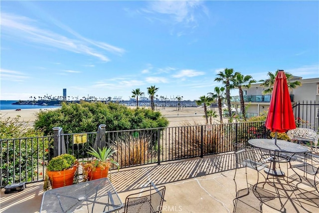 view of patio featuring a water view and fence