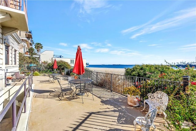 view of patio / terrace featuring outdoor dining area, a view of the beach, and a water view