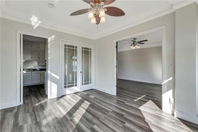 empty room featuring dark wood-style floors, french doors, crown molding, and baseboards