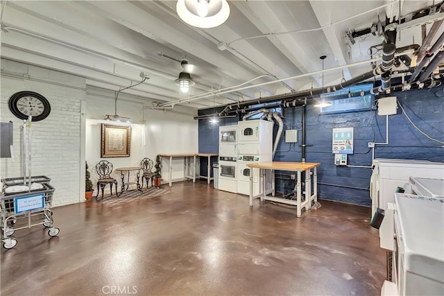 unfinished basement featuring stacked washer and clothes dryer and brick wall