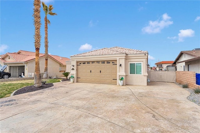 view of front facade featuring concrete driveway, a tiled roof, fence, and stucco siding