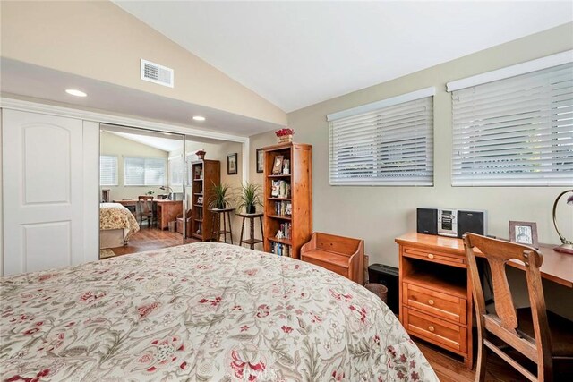 bedroom featuring wood finished floors, visible vents, recessed lighting, vaulted ceiling, and a closet