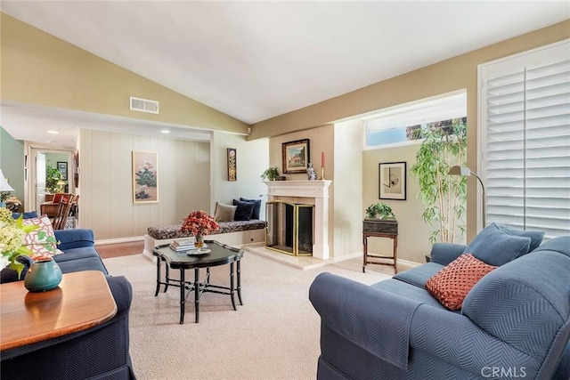 living area featuring visible vents, baseboards, a fireplace, lofted ceiling, and light colored carpet