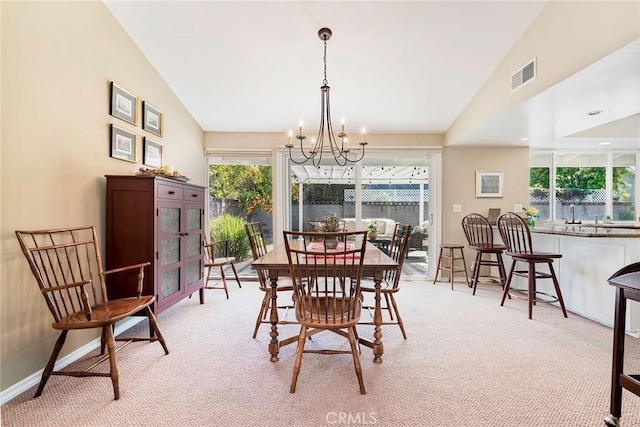 dining room with visible vents, light colored carpet, an inviting chandelier, and vaulted ceiling