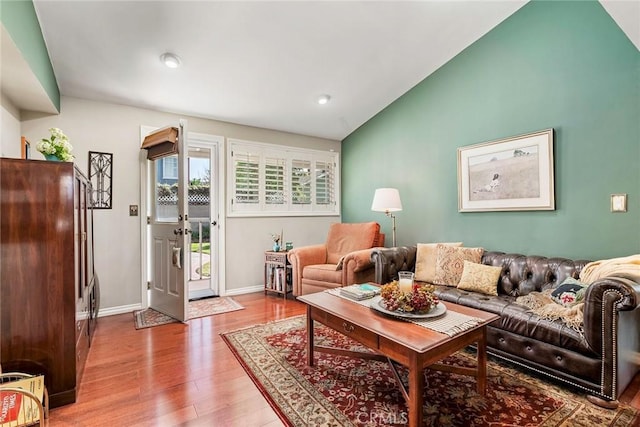 living area featuring wood finished floors, baseboards, and vaulted ceiling