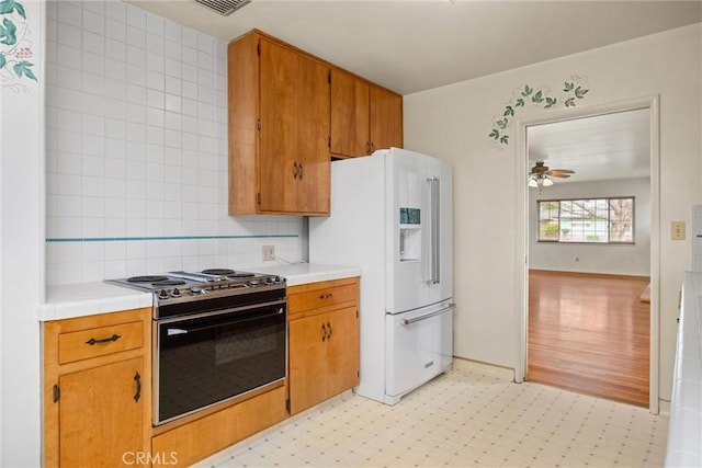 kitchen featuring tasteful backsplash, light floors, light countertops, range with electric stovetop, and white fridge with ice dispenser