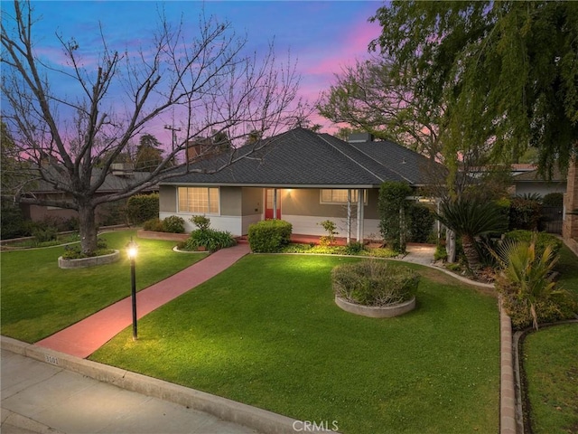 ranch-style house with stucco siding and a yard