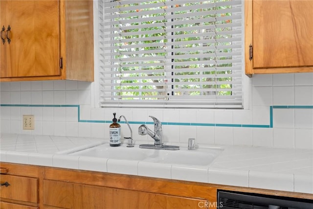 kitchen with tasteful backsplash, plenty of natural light, brown cabinetry, and a sink