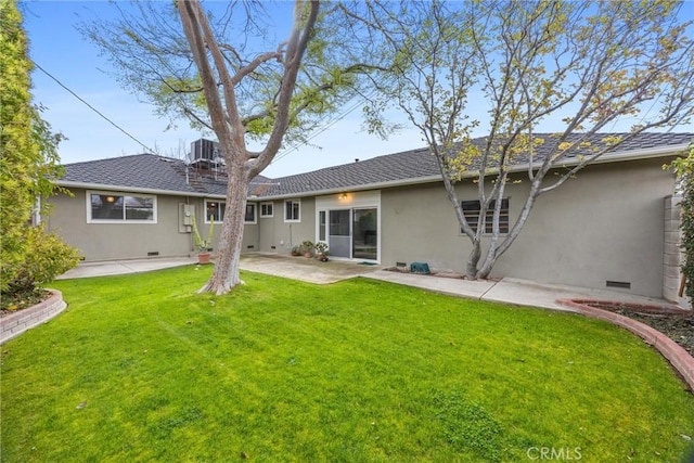 back of house featuring a yard, a shingled roof, stucco siding, crawl space, and a patio area