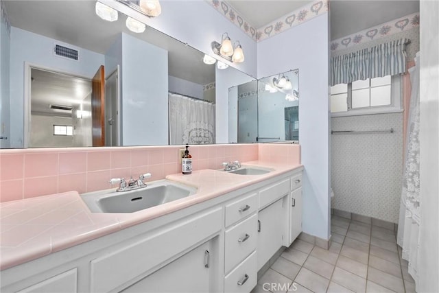 full bathroom featuring wallpapered walls, double vanity, visible vents, and a sink