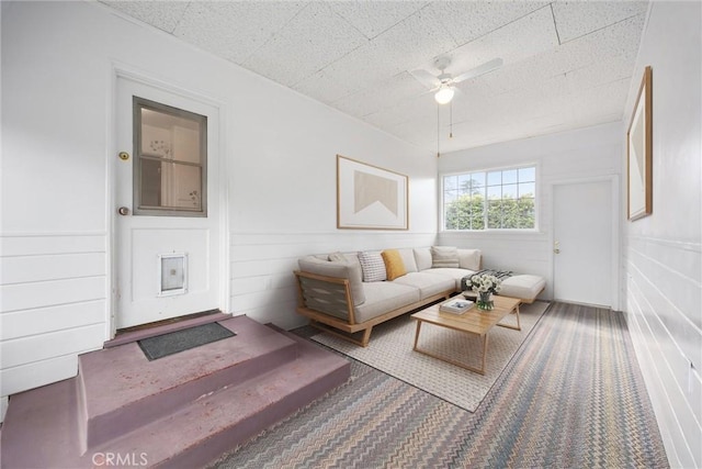 carpeted living area featuring a ceiling fan and a wainscoted wall