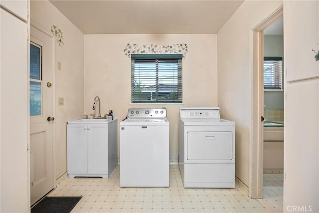 laundry area featuring a sink, washer and dryer, cabinet space, light floors, and a healthy amount of sunlight