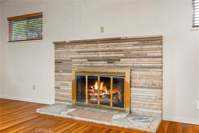 details with a glass covered fireplace, wood finished floors, and baseboards