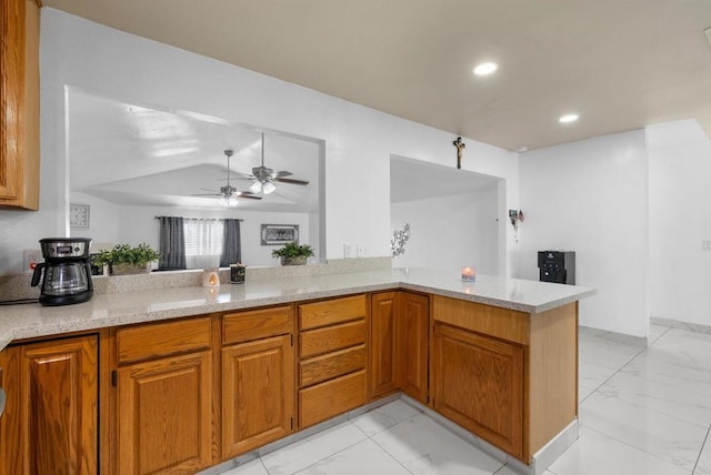 kitchen featuring marble finish floor, a peninsula, and brown cabinets