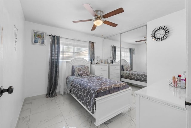 bedroom featuring a closet, marble finish floor, a ceiling fan, and baseboards