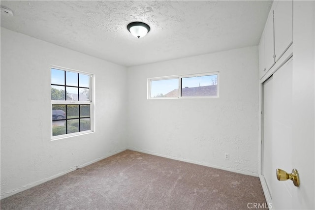 unfurnished bedroom with carpet flooring, a textured wall, and a textured ceiling