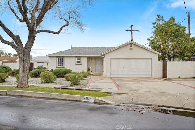 ranch-style house featuring stucco siding, concrete driveway, an attached garage, and fence