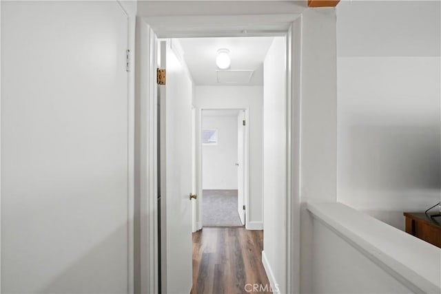 corridor with attic access, wood finished floors, and baseboards