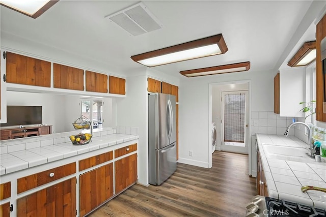 kitchen with visible vents, a sink, dark wood finished floors, freestanding refrigerator, and tile countertops