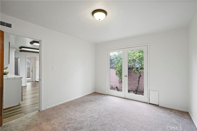 empty room with visible vents, french doors, baseboards, and carpet