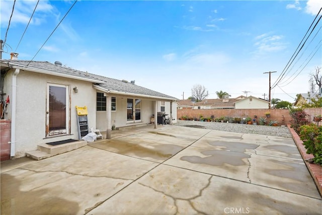 back of house featuring a shingled roof, a patio area, fence, and stucco siding