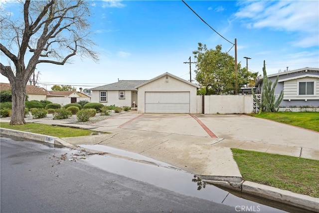 view of front of property with concrete driveway, an attached garage, fence, and stucco siding