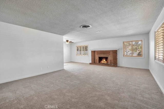 unfurnished living room with visible vents, carpet flooring, a fireplace, baseboards, and ceiling fan