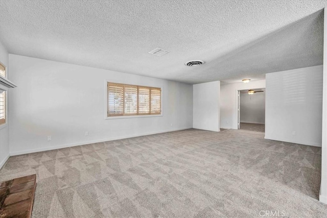 carpeted spare room with visible vents and a textured ceiling