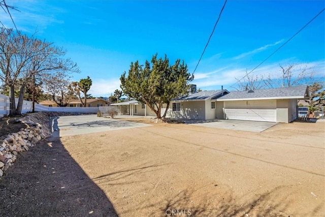 view of front of home with stucco siding, a garage, driveway, and fence