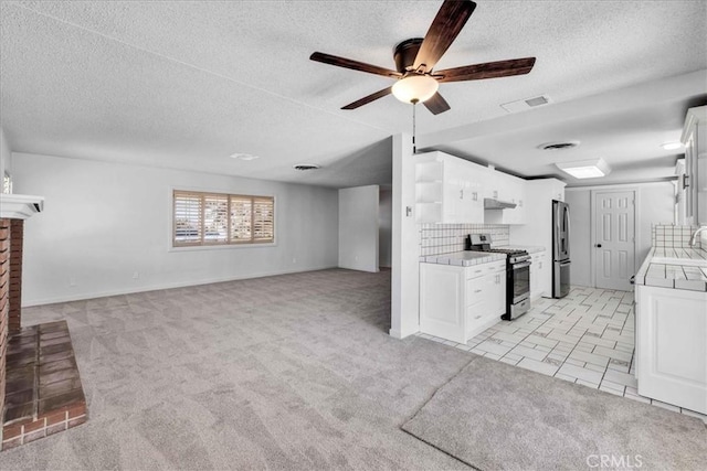 kitchen with visible vents, light carpet, a fireplace, stainless steel appliances, and white cabinetry