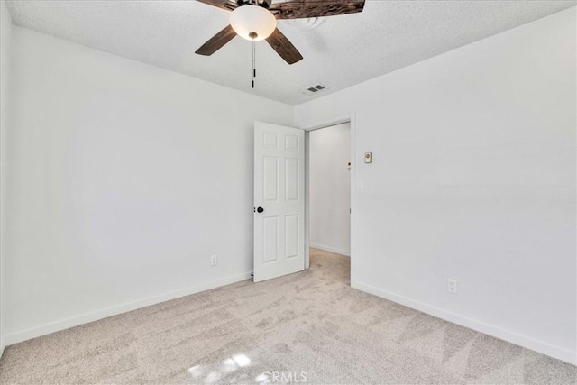 unfurnished room featuring baseboards, light colored carpet, visible vents, and a textured ceiling