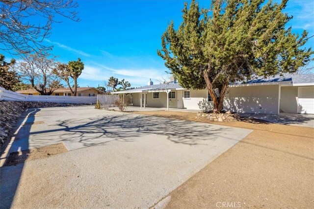 view of front of house featuring stucco siding, a patio area, driveway, and fence