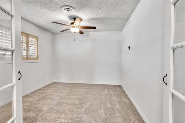 unfurnished room with visible vents, baseboards, ceiling fan, a textured ceiling, and light carpet