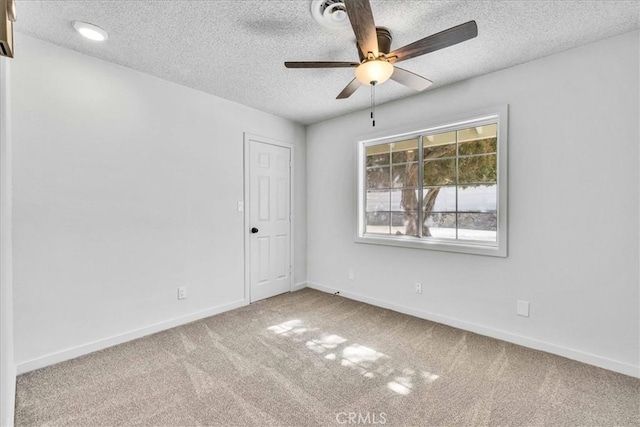 empty room with baseboards, a textured ceiling, ceiling fan, and carpet flooring