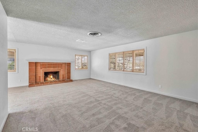 unfurnished living room with visible vents, a fireplace, baseboards, and carpet floors