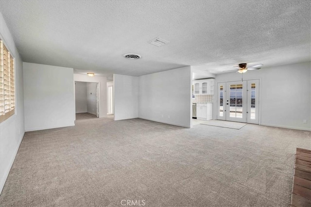 unfurnished living room featuring french doors, carpet floors, and visible vents