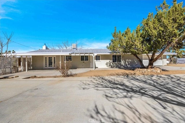 ranch-style house featuring a carport, concrete driveway, and stucco siding