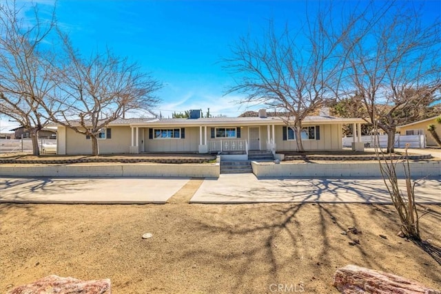 ranch-style house with board and batten siding, fence, and covered porch