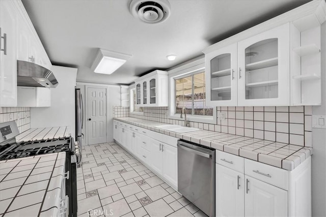 kitchen featuring visible vents, a sink, extractor fan, tile counters, and appliances with stainless steel finishes