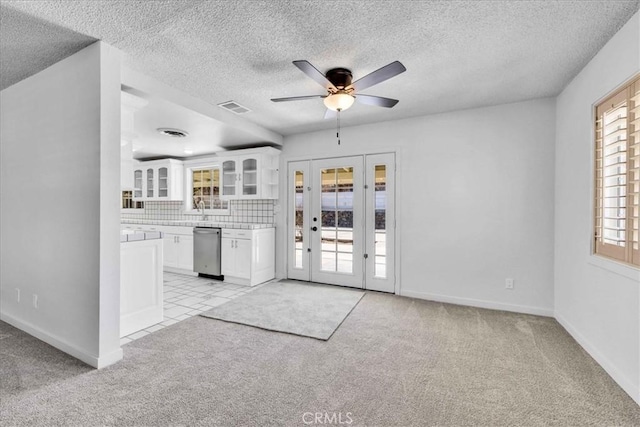 unfurnished living room featuring light carpet, visible vents, french doors, and ceiling fan