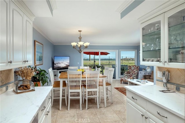 dining space with light tile patterned floors, a notable chandelier, and crown molding