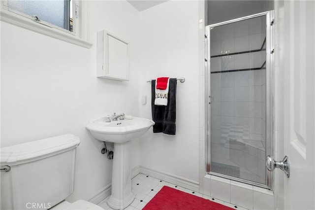 bathroom with a shower stall, toilet, baseboards, and a sink